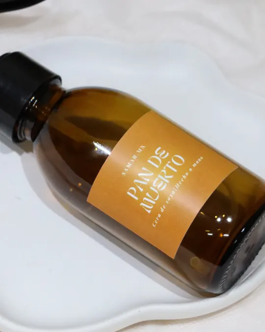 Botella ámbar del aromatizante Pan de muerto de Samar.mx sobre un plato blanco