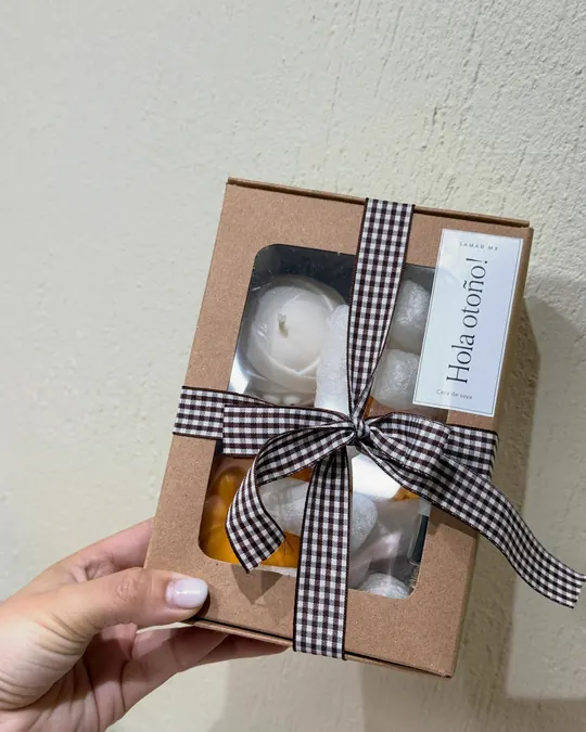 Mano sosteniendo una caja de regalo de Samar.mx con moño de cuadros y etiqueta ¡Hola otoño!