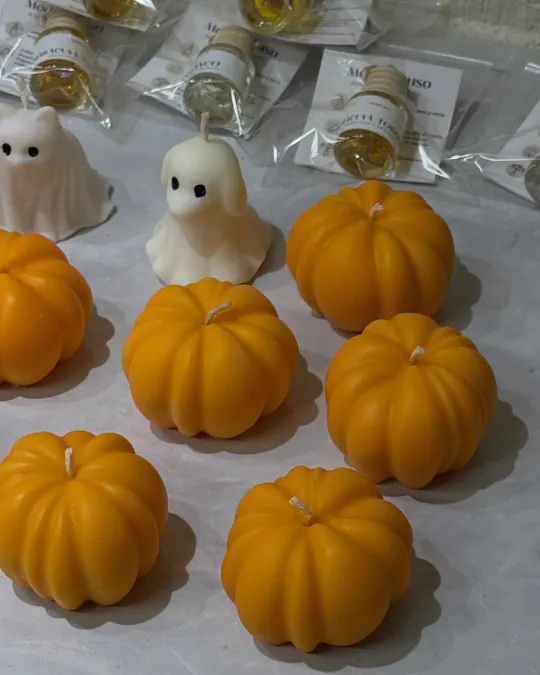 Velas naranjas en forma de calabaza junto a un fantasma de cera