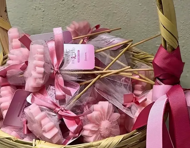 Canasta con velas rosas en forma de flor, envueltas en tul con moño y tarjeta